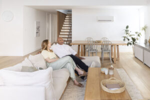 Couple relaxing on a sofa in a bright modern living room cooled by a Daikin split system air conditioner.
